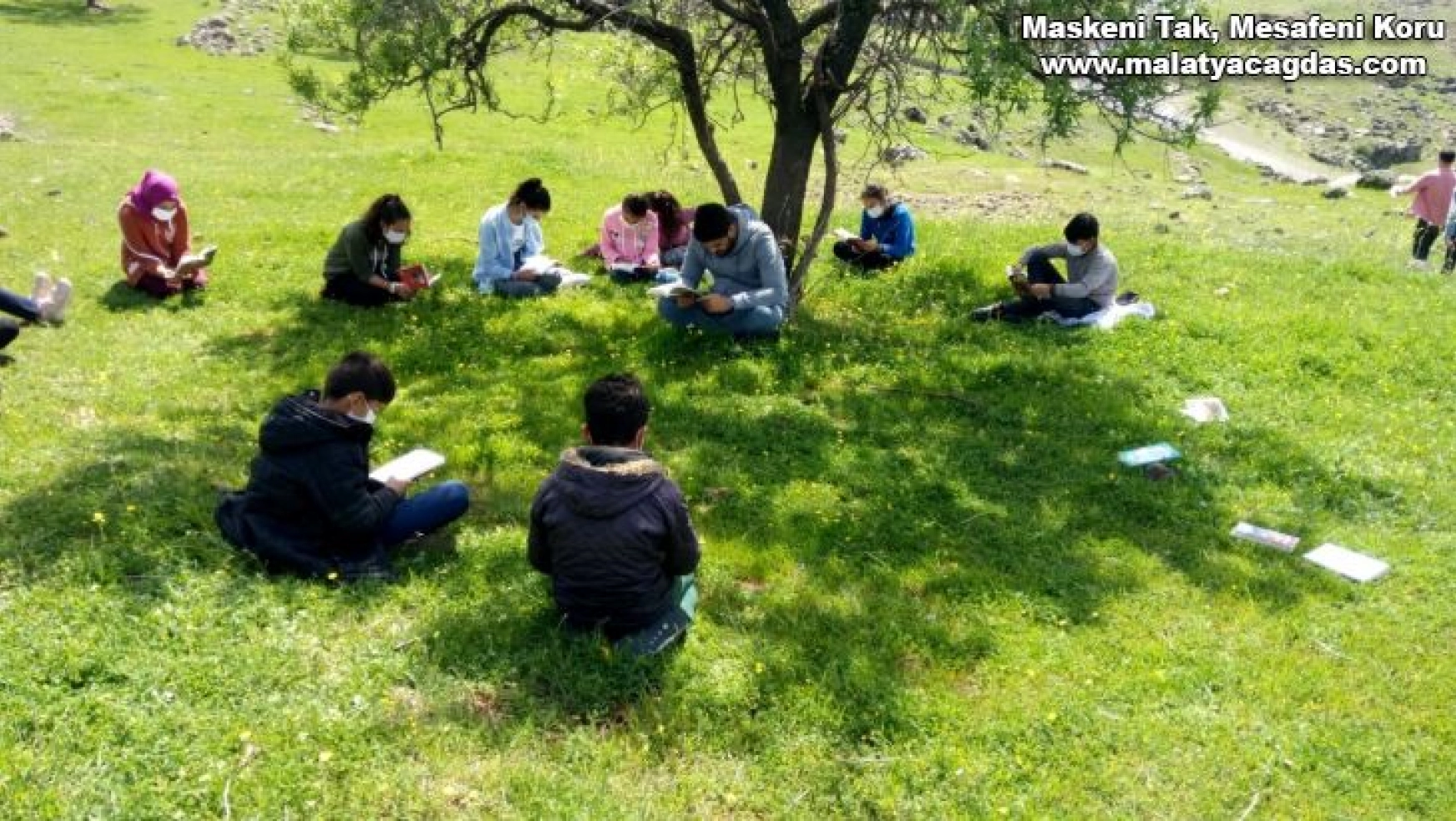 Öğrenciler güneşli havada okuma şenliğinde kitap okudu