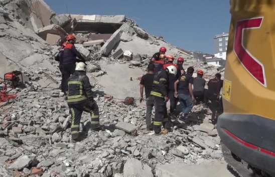 Ağır hasarlı bina yıkılırken iş makinesinin üzerine devrildi
