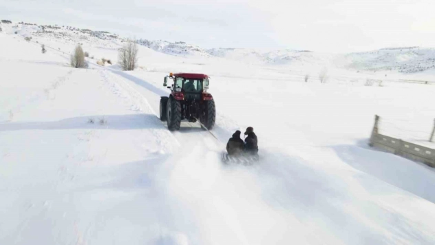 Kar yağışını fırsata çevirdiler, traktörün arkasında kayarak eğlendiler